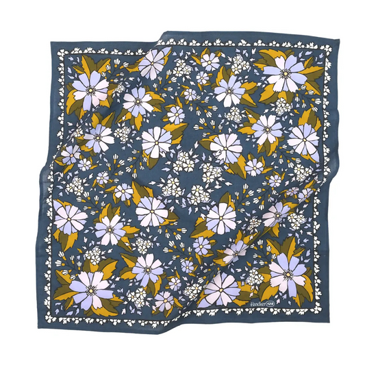 Cornflower blue bandana featuring a white floral border and a white and yellow floral design all over.