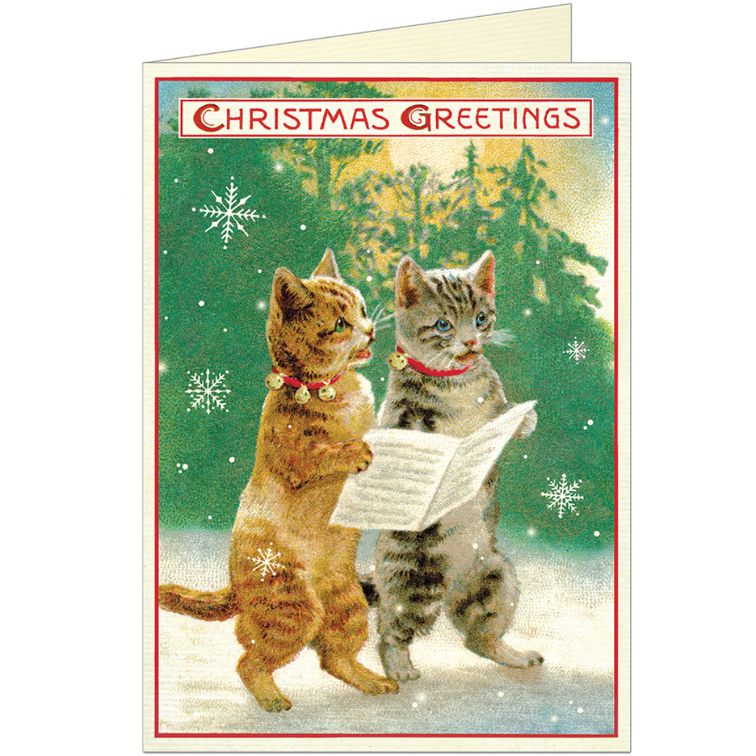 Christmas greeting card featuring a gray cat and an orange cat holding sheet music with the words "Christmas Greetings" above in red font.