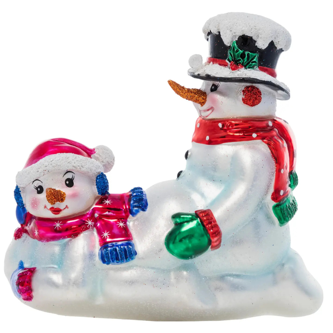 Girly snowman wearing a Santa and a red scarf lying down in front of a boy snowman wearing a top hat, scarf and a carrot nose. Ornament features a shiny white paint with glitter.