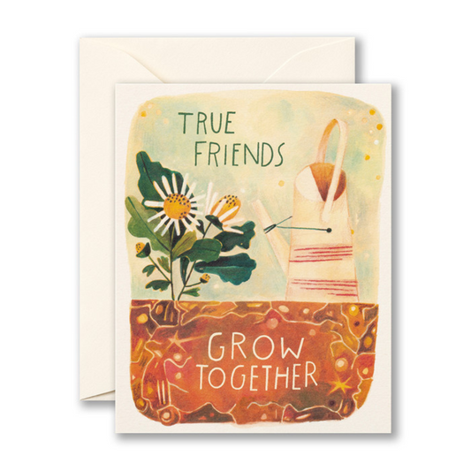 White greeting card featuring the words "TRUE FRIENDS GROW TOGETHER" beside a watering can and white bouquet of daisies.