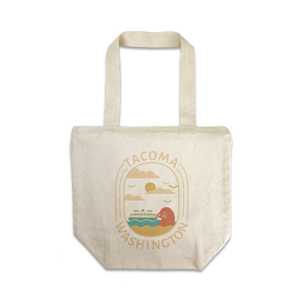 Canvas tote bag featuring a Tacoma skyline design with a seal and ferry boat in the water surrounded by the words "Tacoma, Washington".