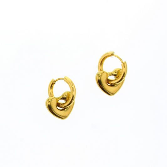 Small gold hoop earrings with heart shaped beads dangling from the hoops