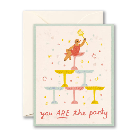 Birthday card featuring a dog in a dress atop a tower of champagne glasses. "You ARE the party"