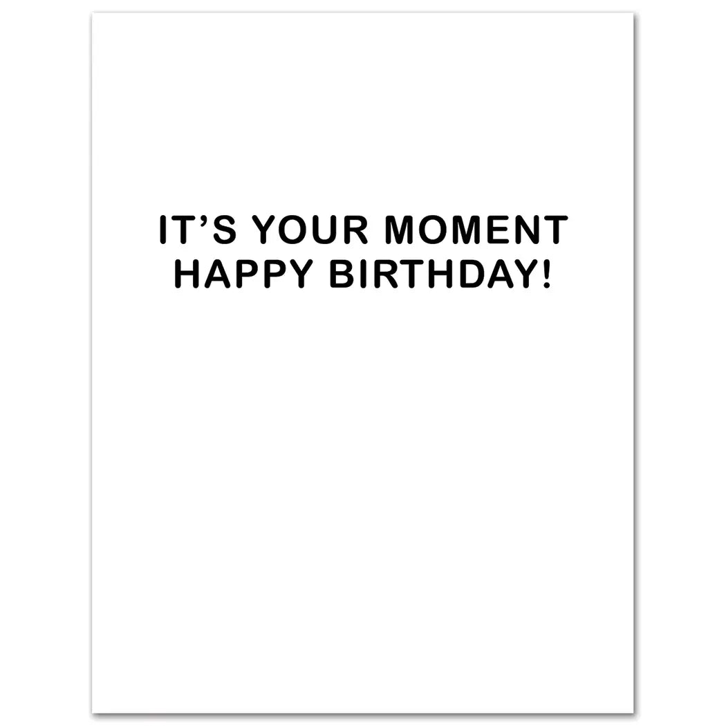 White card with black text 'IT'S YOUR MOMENT HAPPY BIRTHDAY!' on a white background