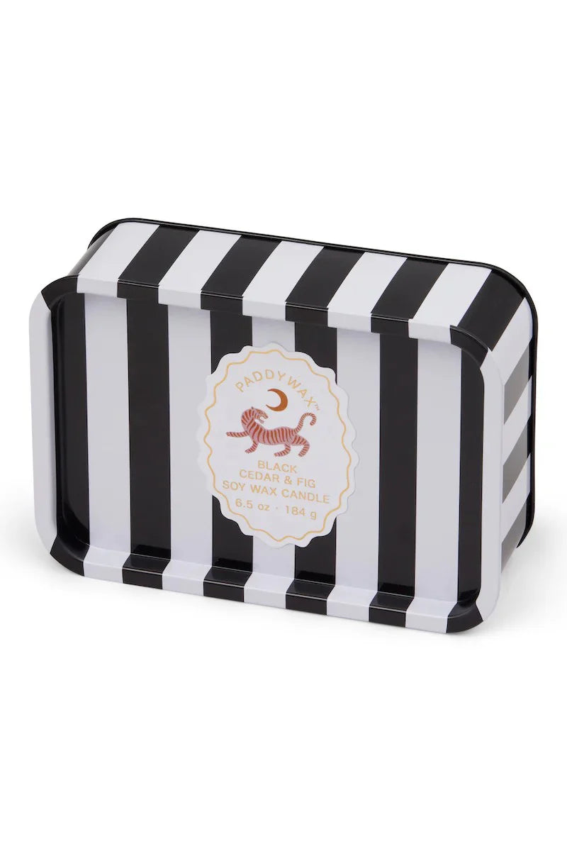 Black and white striped tin with a white label. Label has a tiger and moon on it and reads "Paddywax, Black Cedar & Fig Soy Wax Candle