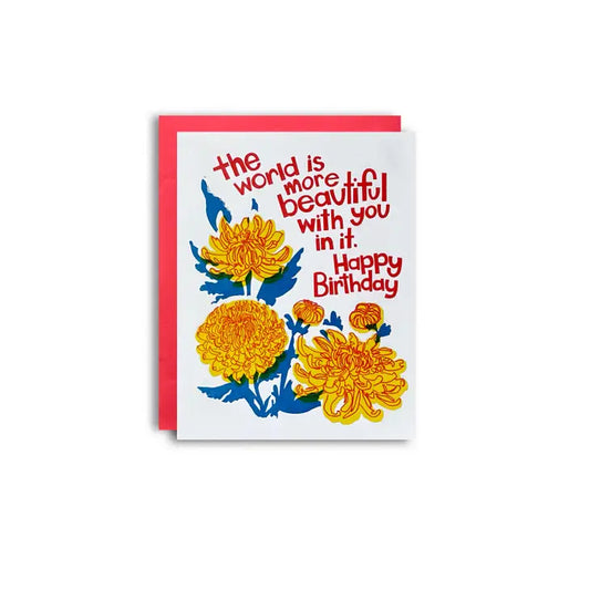 Letterpress card with yellow mum flowers and red text that reads "the world is more beautiful with you in it. Happy Birthday"