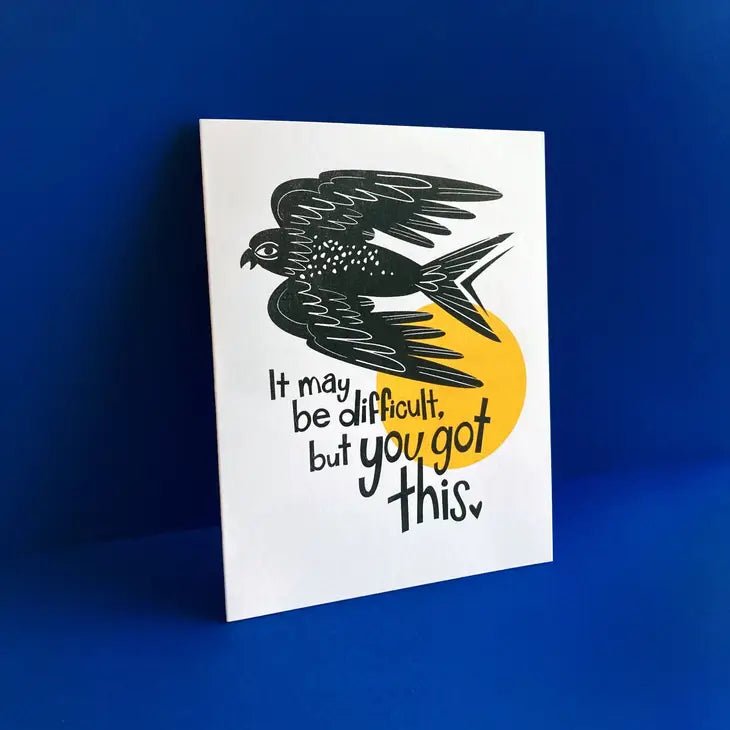 yellow envelope underneath white card, print of black bird and text reading "it may be difficult, but you got this"