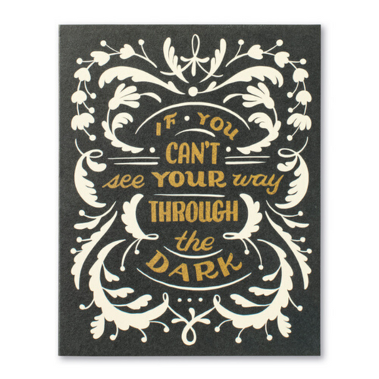 Black card with white decorations and gold letters. "If you can't see your way through the dark..."